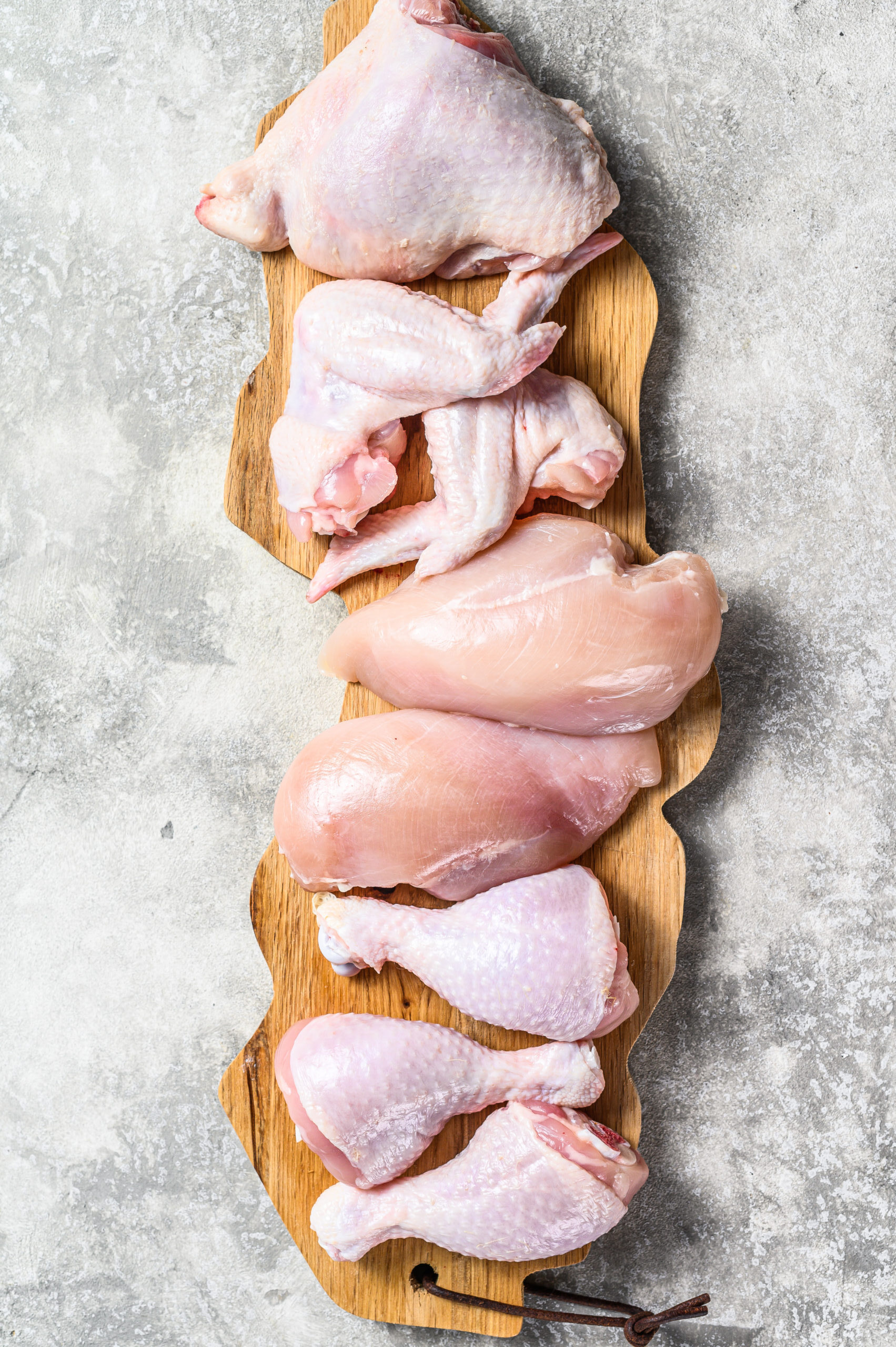 Raw uncooked chicken meat on a cutting board. Gray background. Top view.